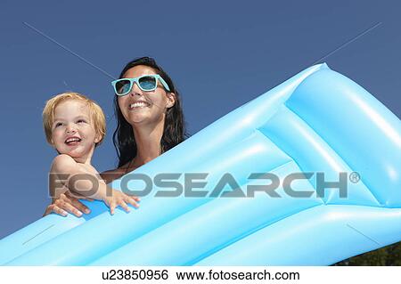 Stock Photograph - Mother and son holding an air bed. Fotosearch