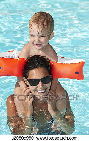 Stock Image - Mother and son playing in swimming pool. Fotosearch