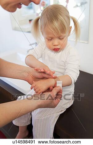 Mother putting bandage on toddler girl View Large Photo Image Stock Image - Mother putting bandage on toddler girl. Fotosearch