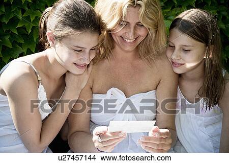Picture - Mum and daughters look at photos. Fotosearch