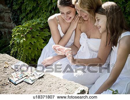 Stock Photo - Mum and daughters looking at family pics. Fotosearch