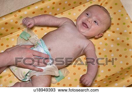 Stock Image - Mum changing nappy to her newborn. Fotosearch