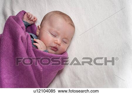 Stock Photography - Newborn sleeping on lilac blanket. Fotosearch