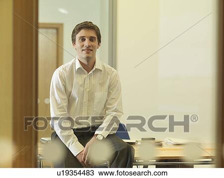 Office man sitting on desk View Large Photo Image Stock Image - Office man sitting on desk. Fotosearch