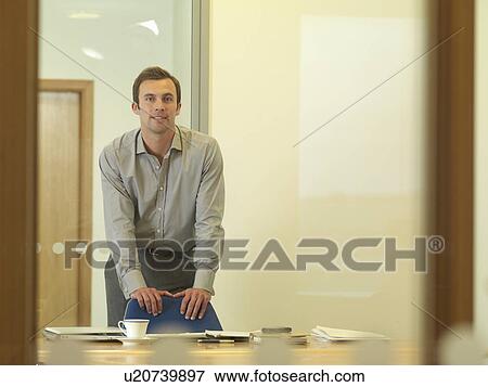 Office man standing at desk View Large Photo Image Stock Photo - Office man standing at desk. Fotosearch
