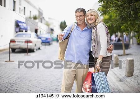 Older couple carrying shopping bags View Large Photo Image Stock Photo - Older couple carrying shopping bags. Fotosearch