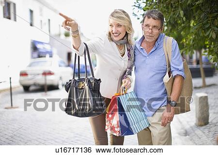 Stock Photograph - Older couple carrying shopping bags. Fotosearch