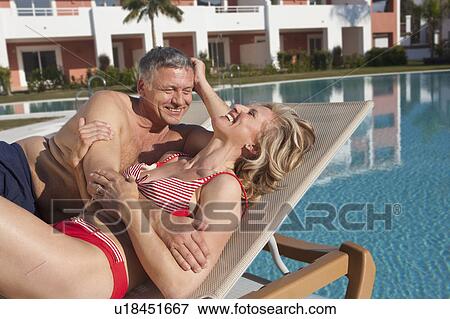 Older couple laughing on sunbeds by pool View Large Photo Image Stock Photo - Older couple laughing on sunbeds by pool. Fotosearch