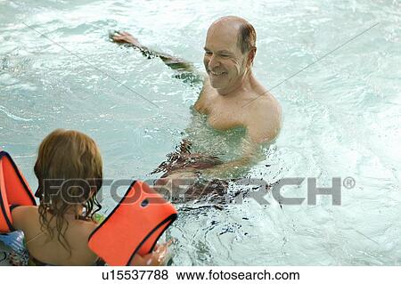 Stock Photo - Older man swimming with grandchild. Fotosearch