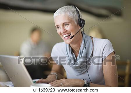Older woman in headset using laptop View Large Photo Image Stock Image - Older woman in headset using laptop. Fotosearch