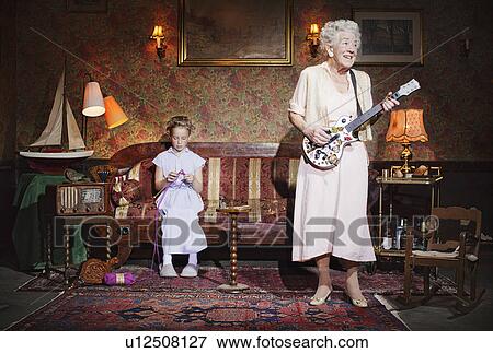 Older woman playing guitar as girl knits View Large Photo Image Stock Photo - Older woman playing guitar as girl knits. Fotosearch