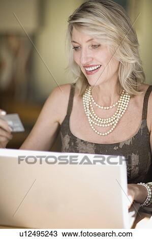 Stock Image - Older woman shopping on the internet. Fotosearch