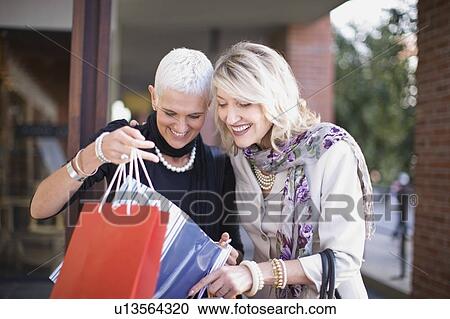 Older women examining shopping bags View Large Photo Image Stock Image - Older women examining shopping bags. Fotosearch