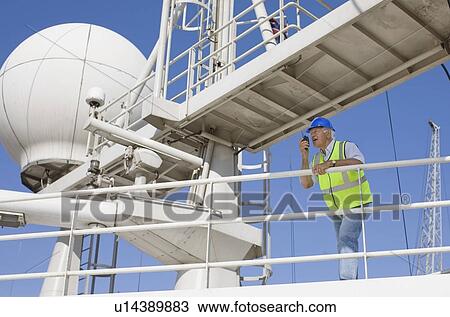 Stock Image - Older worker standing on guardrail. Fotosearch
