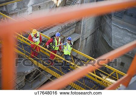 Stock Photograph - People crossing a bridge in a dockyard. Fotosearch