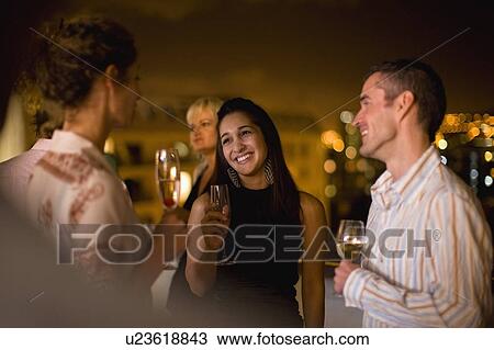 Stock Image - People having wine on terrace at night. Fotosearch