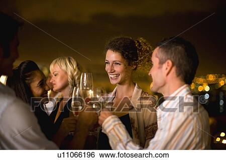 Stock Photograph - People having wine on terrace at night. Fotosearch