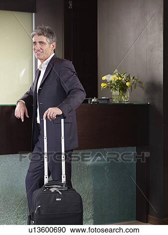 Stock Image - Portrait of senior business man at the front desk of a hotel. Fotosearch
