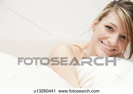 Stock Image - Portrait of young woman in bed. Fotosearch