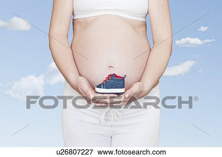 Stock Photo - Pregnancy bump with shoe. Fotosearch