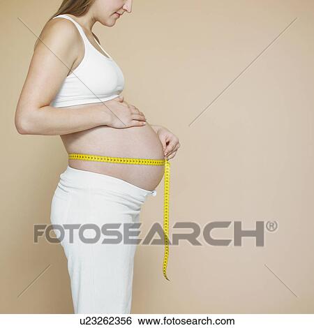 Stock Photograph - Pregnancy bump with with measuring tape, profile. Fotosearch