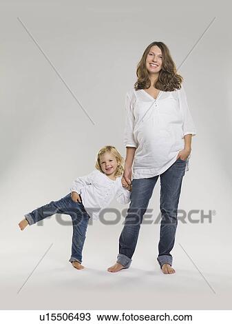 Stock Image - Pregnant woman holding daughter’s hand. Fotosearch