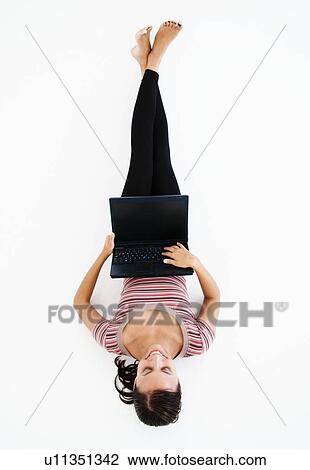 Stock Image - Prone happy woman with laptop. Fotosearch