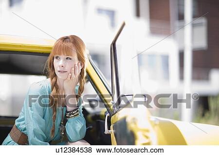 Stock Photo - red haired Woman sitting in a car door open. Fotosearch