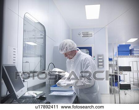Stock Image - Scientist with product in clean room. Fotosearch