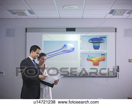 Stock Photo - Scientists discuss notes next to designs. Fotosearch