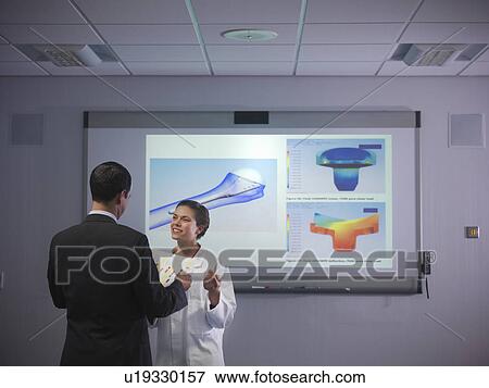 Scientists discuss notes next to designs View Large Photo Image Stock Photo - Scientists discuss notes next to designs. Fotosearch