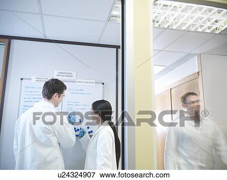 Stock Photo - Scientists look at noticeboard. Fotosearch