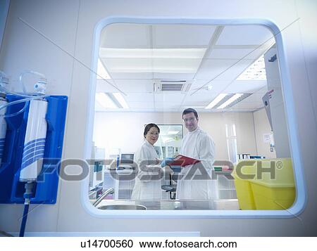 Stock Image - Scientists with notes in clean room. Fotosearch