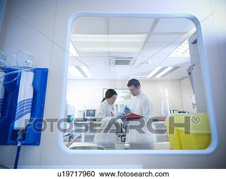 Stock Image - Scientists with notes in clean room. Fotosearch