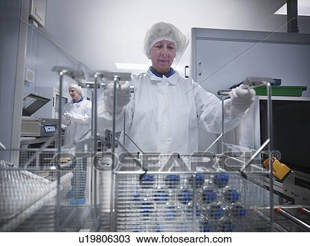 Stock Image - Scientists with product in clean room. Fotosearch