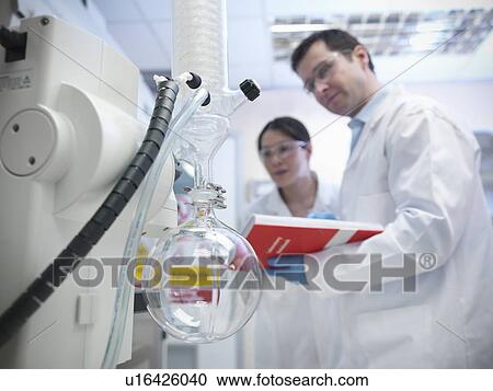 Stock Image - Scientists working with vacuum still. Fotosearch