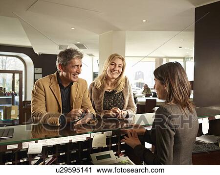 Stock Image - Senior Couple Checking into a Hotel. Fotosearch