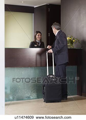 Senior man checking in at front desk of a hotel View Large Photo Image Stock Photo - Senior man checking in at front desk of a hotel. Fotosearch