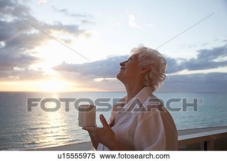Senior Woman drinking coffee at sunrise View Large Photo Image Stock Photography - Senior Woman drinking coffee at sunrise. Fotosearch