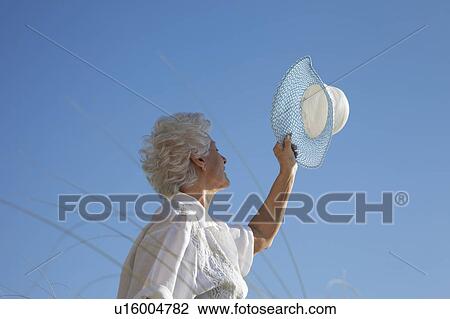Stock Image - Senior Woman holding hat. Fotosearch