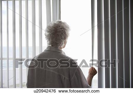 Stock Photograph - Senior Woman looking out of a window. Fotosearch