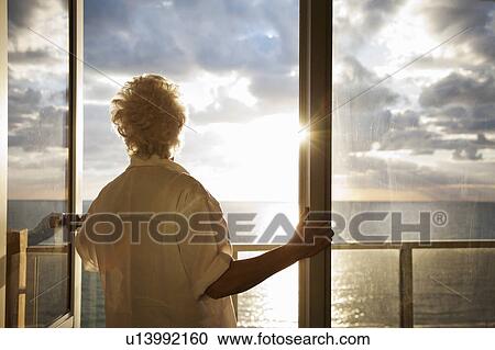 Stock Image - Senior Woman watching sunrise. Fotosearch