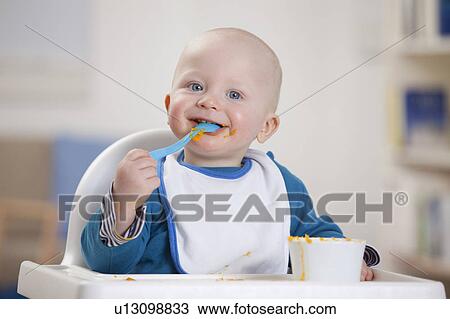 Smiling baby boy eating in high chair View Large Photo Image Stock Image - Smiling baby boy eating in high chair. Fotosearch