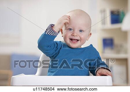Picture - Smiling baby boy sitting in high chair. Fotosearch