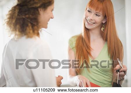 Stock Photo - Smiling businesswomen talking in office. Fotosearch