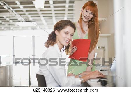 Stock Photograph - Smiling businesswomen working together. Fotosearch