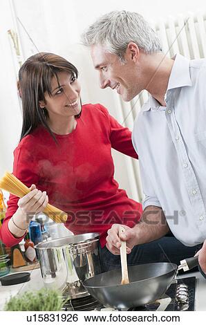 Stock Photograph - Smiling couple cooking together. Fotosearch