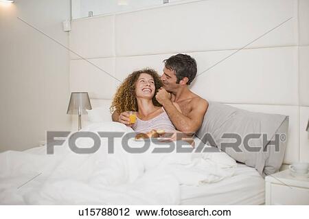 Smiling couple having breakfast in bed View Large Photo Image Stock Image - Smiling couple having breakfast in bed. Fotosearch
