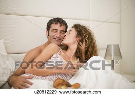 Smiling couple having breakfast in bed View Large Photo Image Stock Photo - Smiling couple having breakfast in bed. Fotosearch