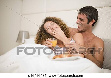 Stock Photography - Smiling couple having breakfast in bed. Fotosearch